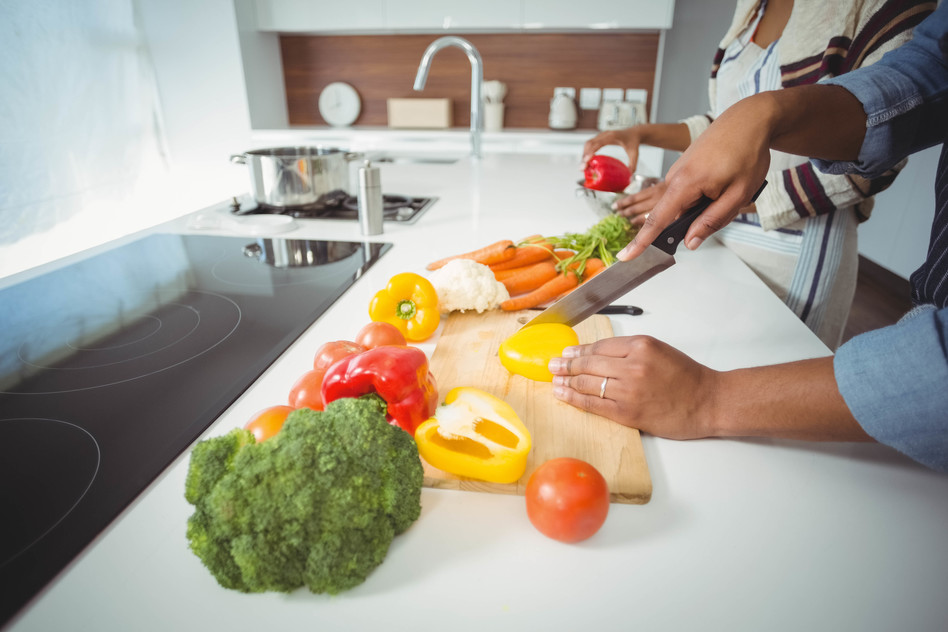 Mid section of couple preparing vegetables in the kitchen