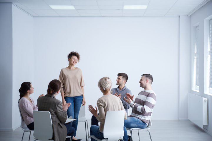 Happy woman talking in front of group during psychotherapy group therapy